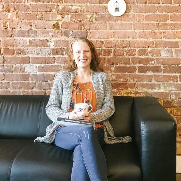woman sitting on couch in front of brick wall