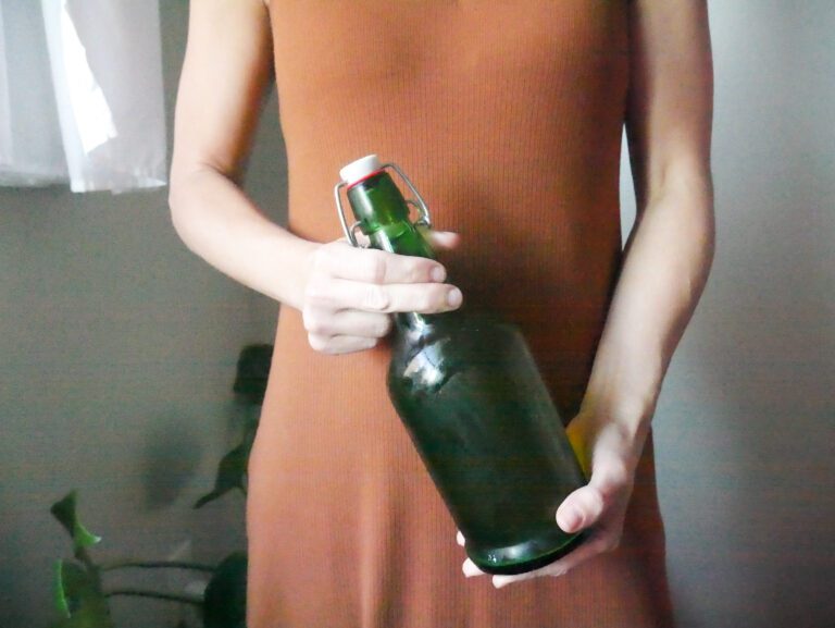 homemade kombucha being held by woman in orange dress