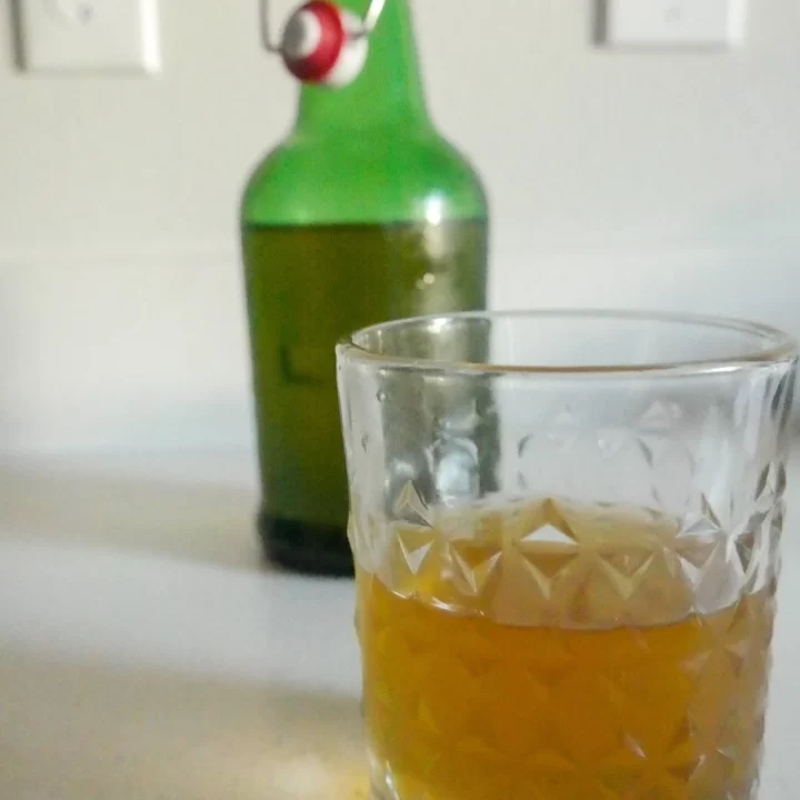 homemade kombucha in clear glass and green flip top bottle