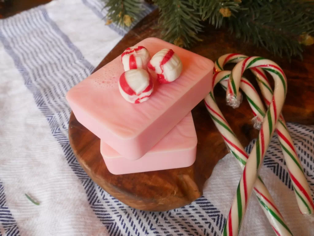candy canes and peppermints sitting around homemade melt and pour red, candy cane soap bars