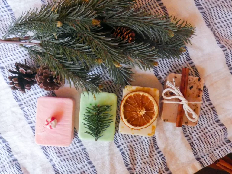 4 homemade melt and pour christmas soaps next to an evergreen branch