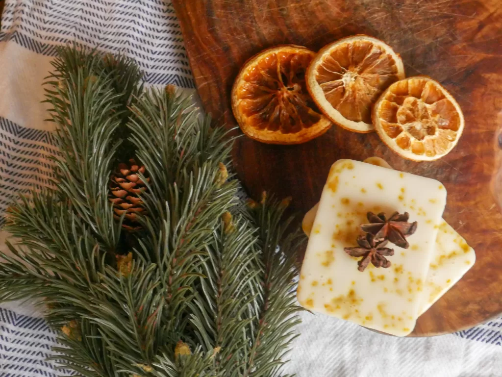 homemade melt and pour vanilla spiced soap with dried oranges and evergreen branch next to it