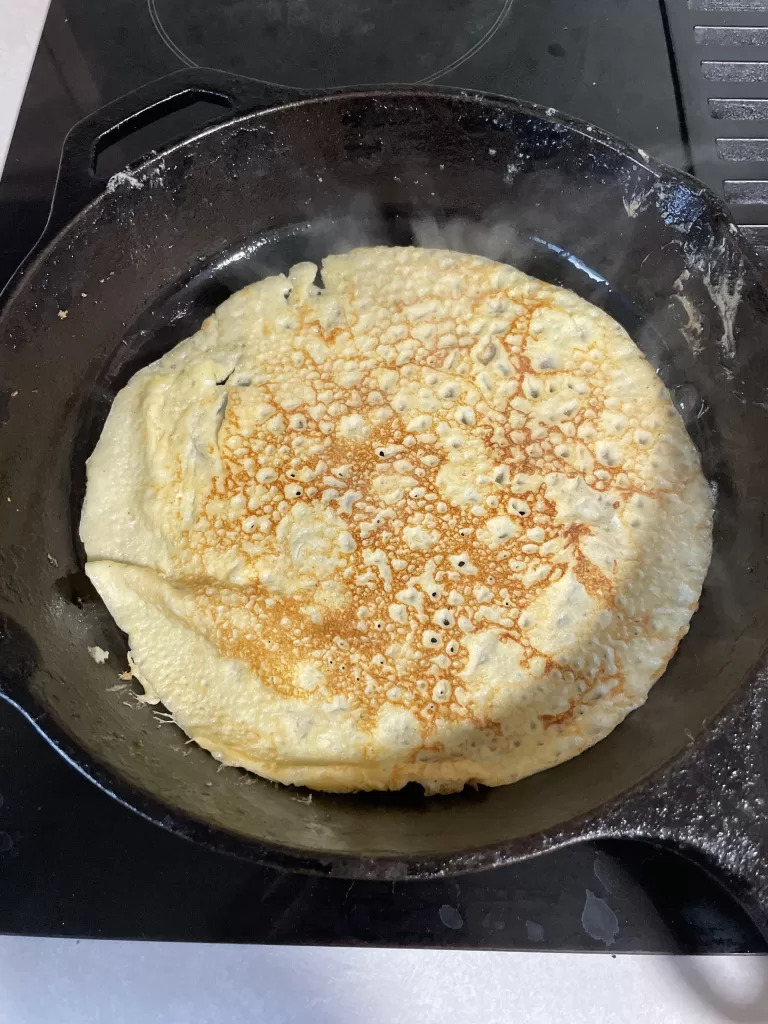 sourdough discard crepe cooking in a cast iron skillet