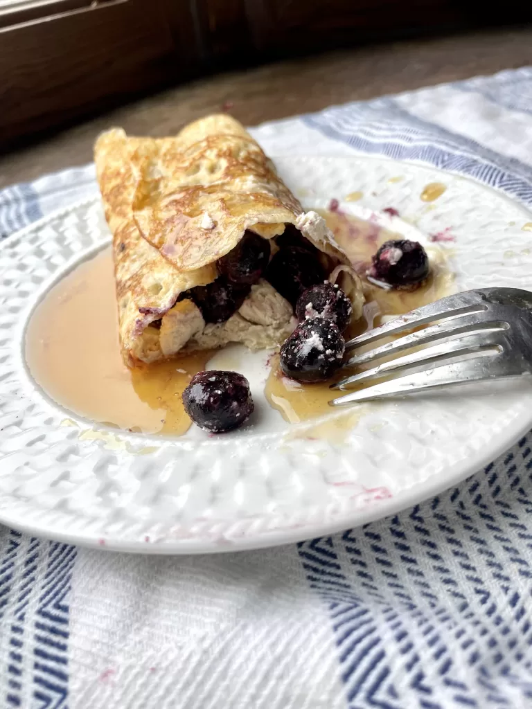 sourdough crepe on a small white plate with a bit taken out of it