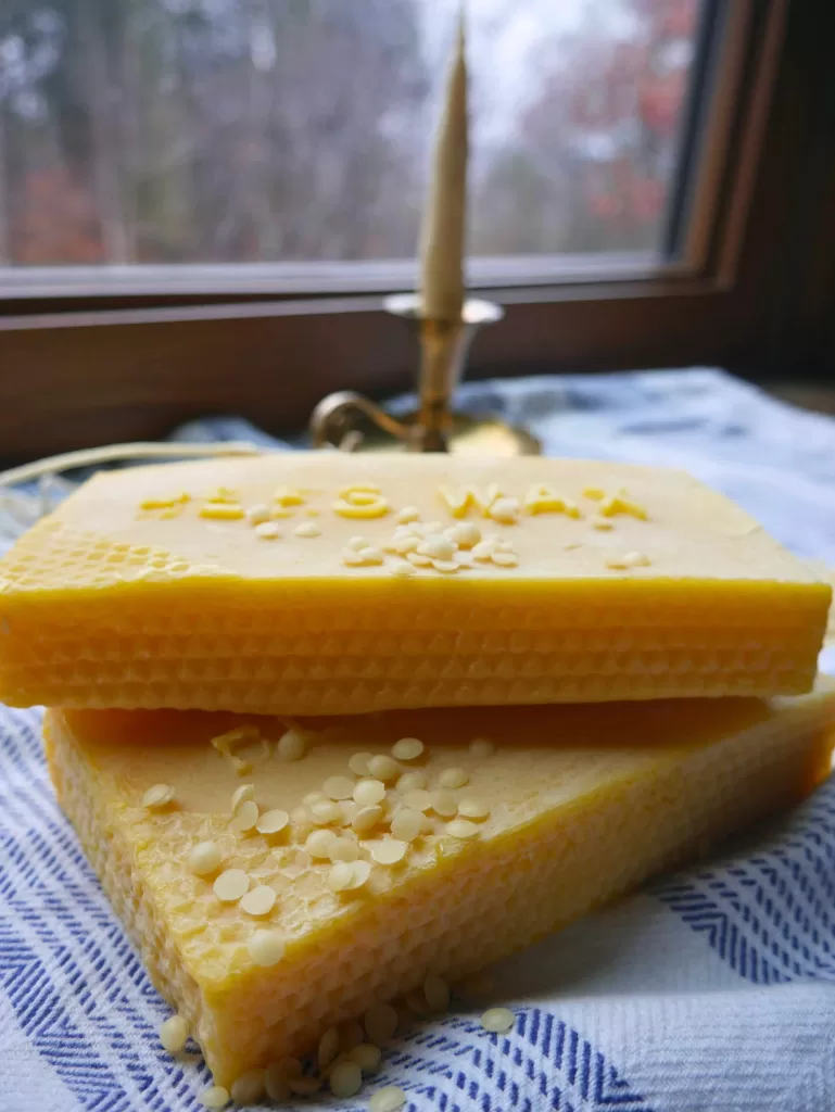 beeswax blocks in front of a brass candle holder with a beeswax candle in it