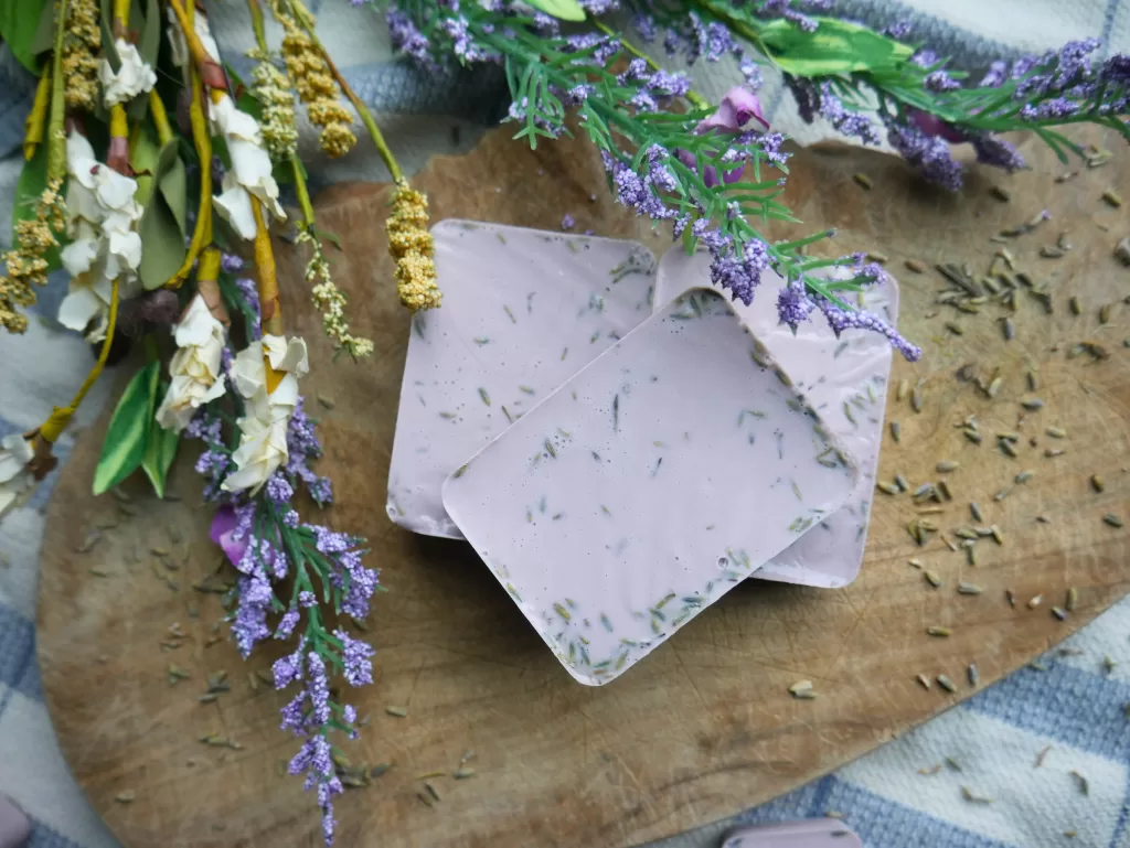 lavender soap sitting by white and purple flowers