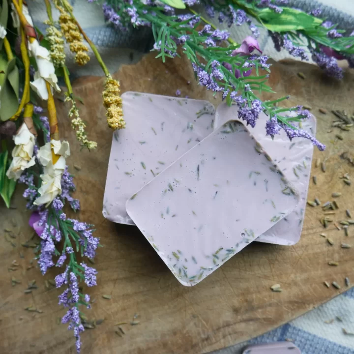 lavender soap sitting by white and purple flowers
