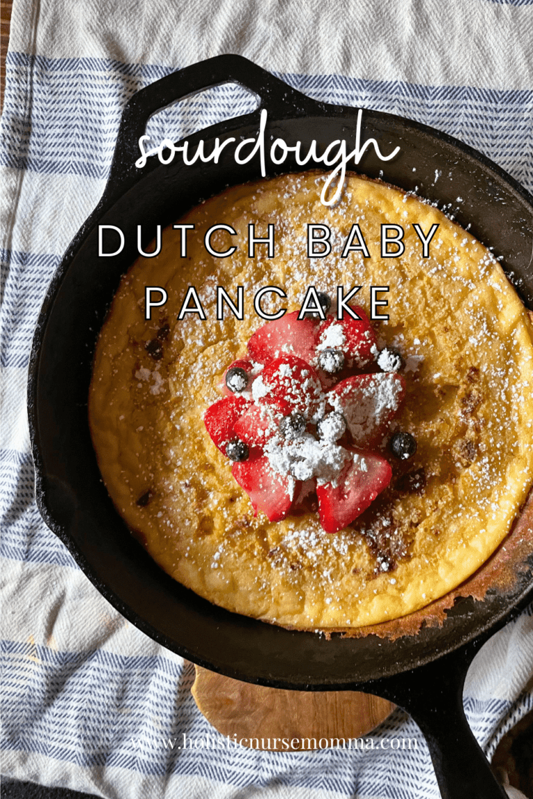 sourdough dutch baby pancake with fruit and powdered sugar on top in a cast iron skillet