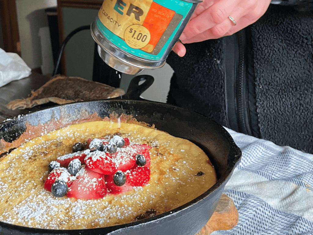 dusting sourdough dutch baby pancake with powdered sugar