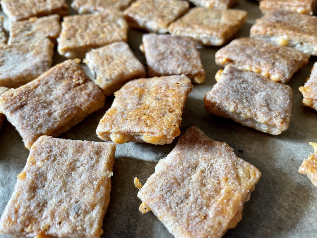 sourdough discard crackers made with cheese and freshly milled flour laying on parchment paper