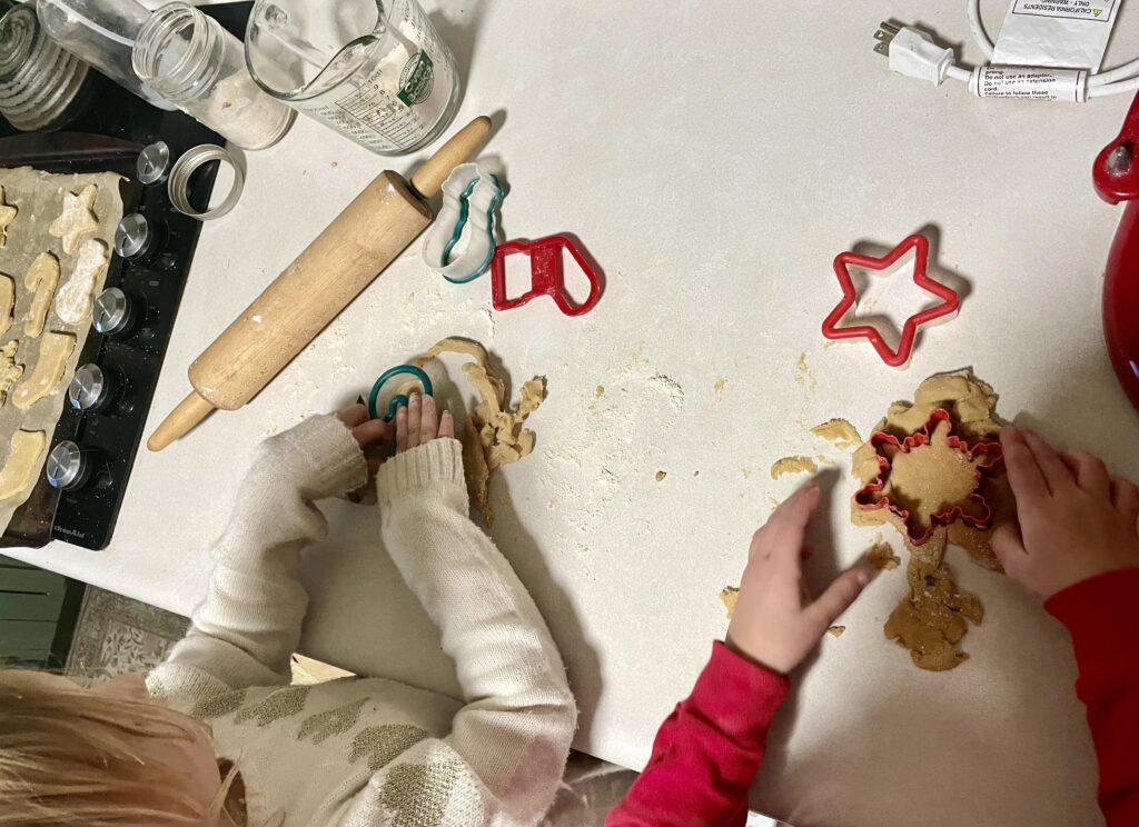 kids' hands using cookie cutters to cut out fresh milled flour sugar cookies