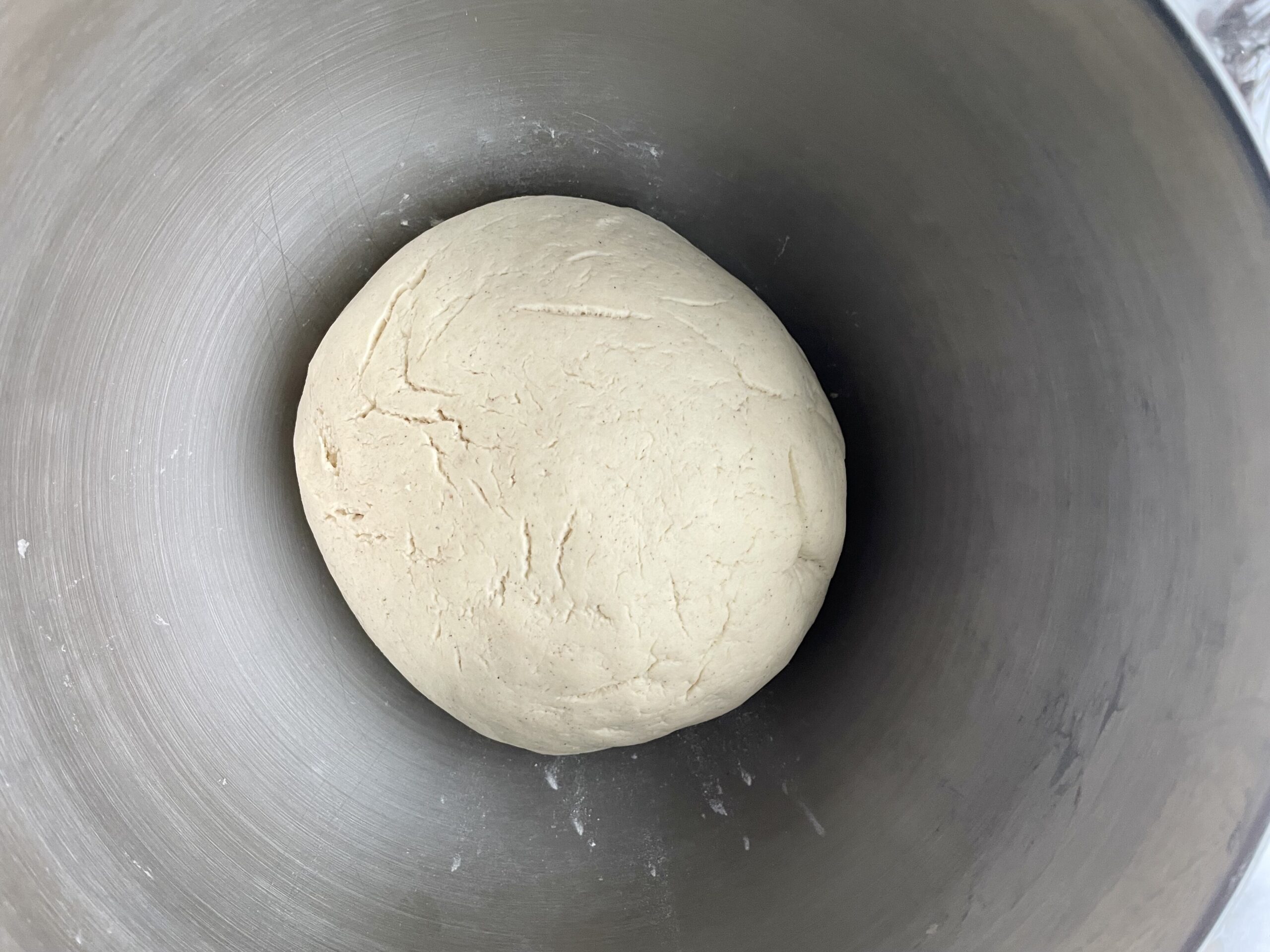 smooth, risen gluten free cinnamon roll dough ball in silver bowl