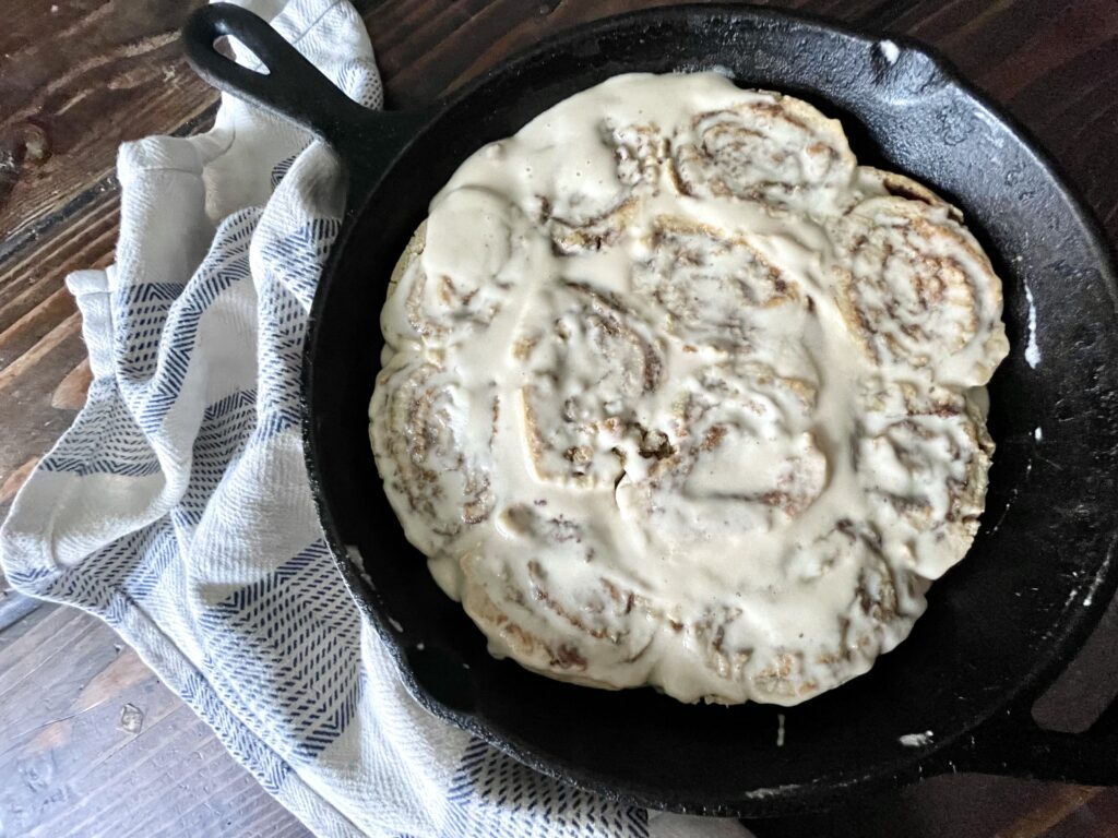 frosted gluten free cinnamon rolls in a cast iron pan