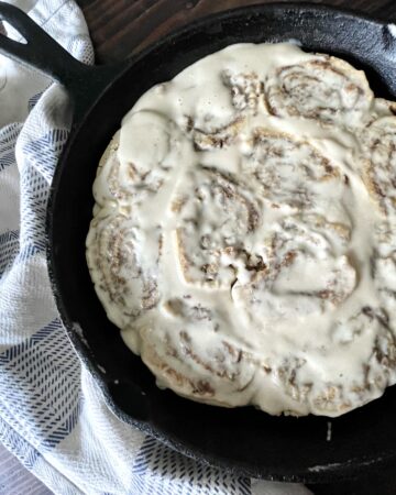 frosted gluten free cinnamon rolls in a cast iron pan