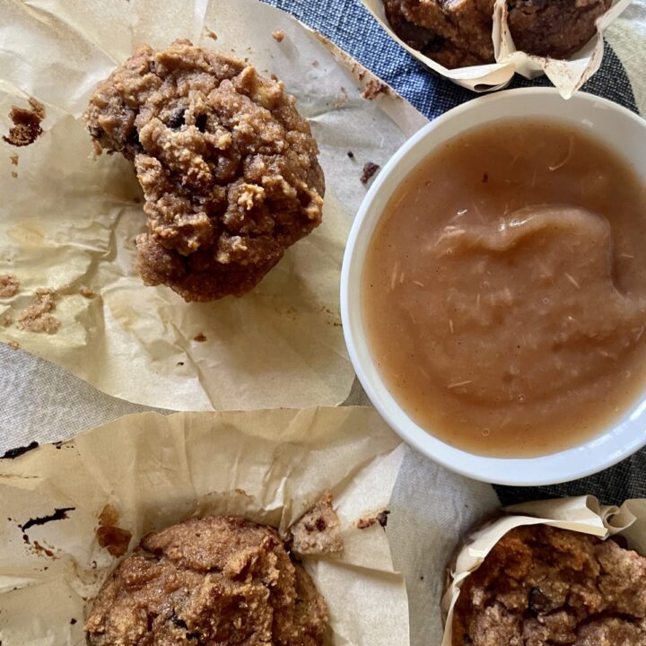 applesauce muffin with bite out of it next to a bowl of applesauce