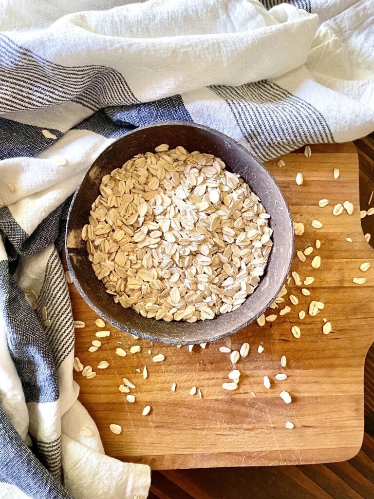 uncooked bowl of oatmeal on wooden cutting board
