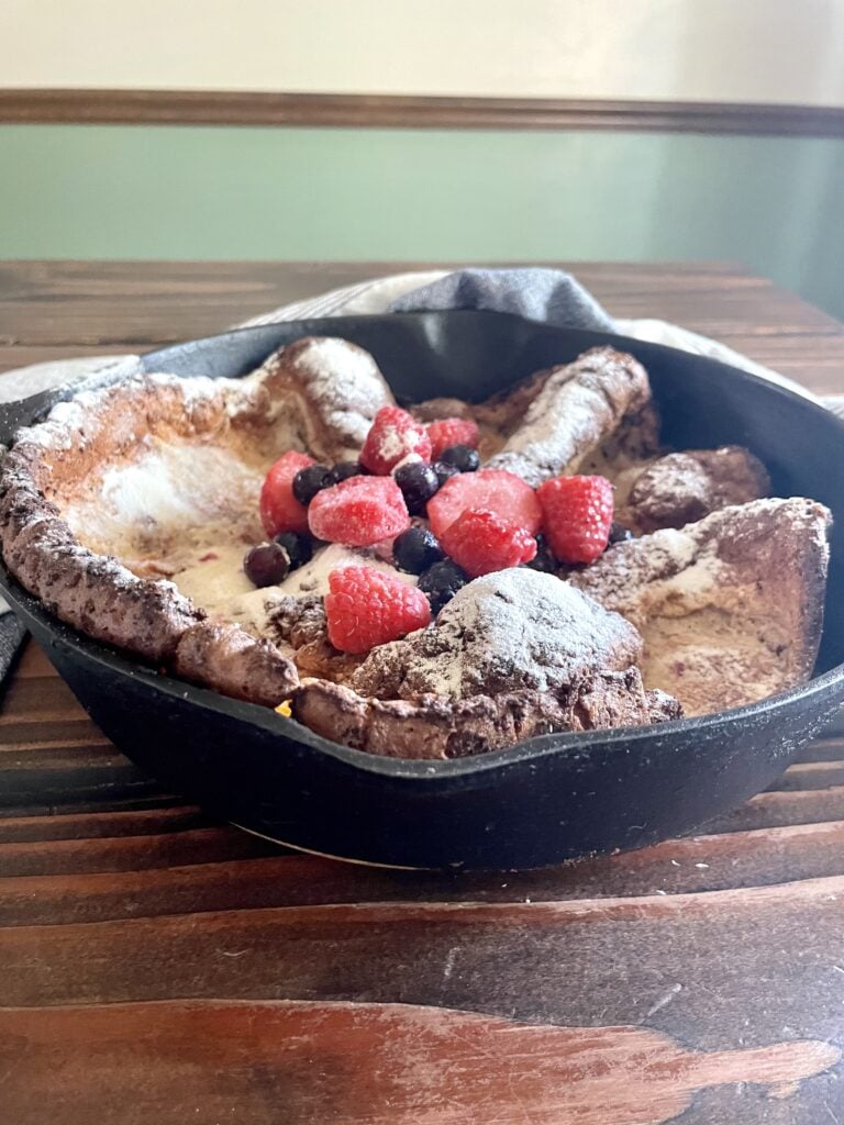 fresh milled flour dutch baby pancake with fresh fruit on top in a cast iron skillet