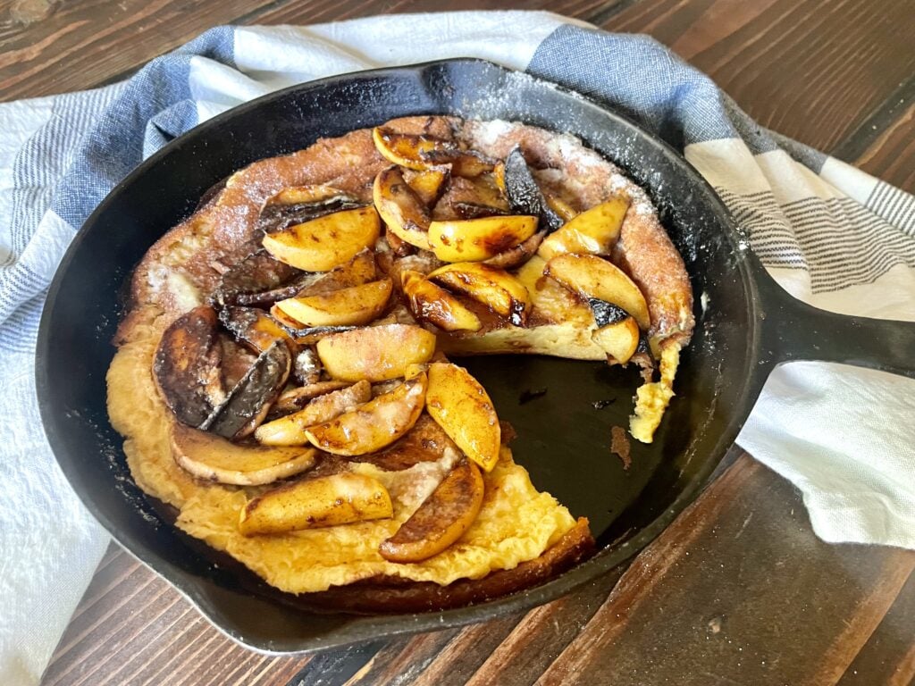 fresh milled flour dutch baby pancake in cast iron pan with cinnamon-sugar apples on top
