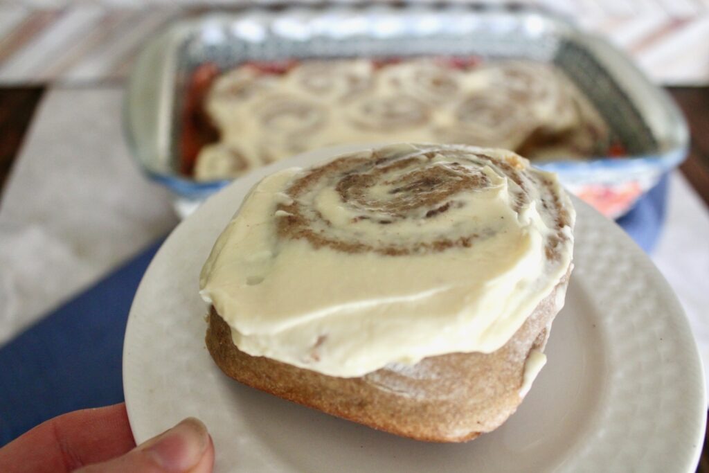 one no refined sugar fresh milled flour sourdough cinnamon roll with cream cheese icing on white plate